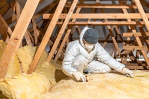 A professional installing new insulation in the attic